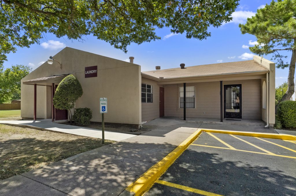 the exterior of a building with parking lot and trees at The Northwood Apartments