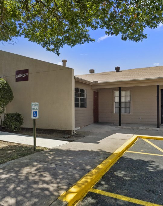 the exterior of a building with parking lot and trees at The Northwood Apartments