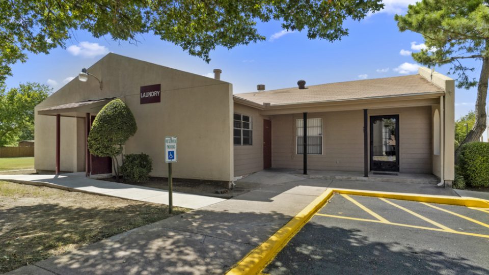 the exterior of a building with parking lot and trees at The Northwood Apartments