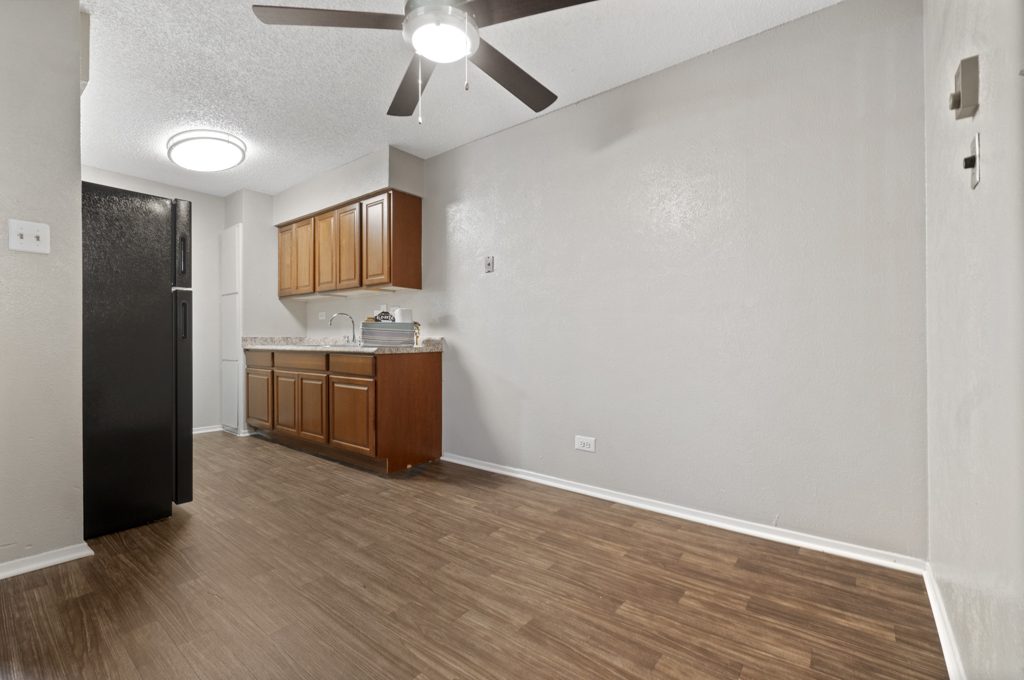 an empty kitchen with a ceiling fan and hardwood floors at The Northwood Apartments