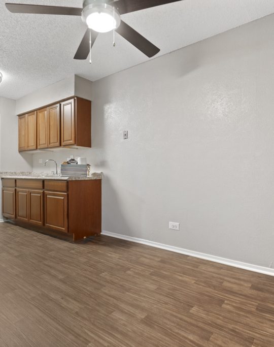 an empty kitchen with a ceiling fan and hardwood floors at The Northwood Apartments