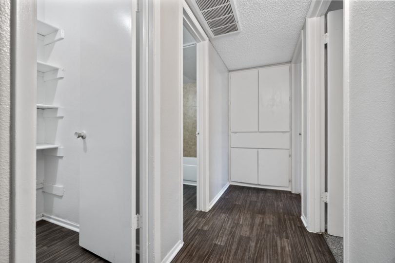 a hallway with white walls and wood floors at The Northwood Apartments