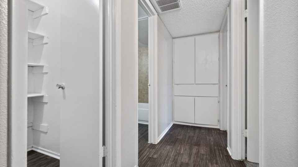 a hallway with white walls and wood floors at The Northwood Apartments